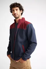 Campera polar para hombre, color azul marino con canesú y cuello en color borgoña. Tiene cierre frontal completo, bolsillos laterales con cierre, puños y ruedo elastizados, y logo estampado en el pecho.