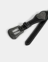 Cinturón negro de cuero sintético con hebilla metálica labrada y apliques de corazones metálicos con diseño floral.