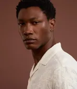 Camisa de manga corta color crema con bordado floral texturizado, cuello solapa y abotonadura frontal.