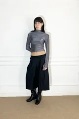 Polera gris de lycra, ajustada y de manga larga, diseñada para adaptarse a diversas siluetas.