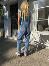 Mono largo de jean con estampado de hojas en tonos azules, marrones y verdes. Tiene botones frontales, corte vintage y bolsillos laterales.