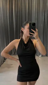 Minivestido negro ajustado al cuerpo, con escote halter y espalda descubierta.
