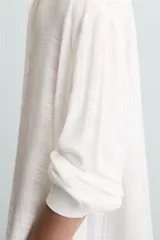 Camisa de hombre color blanco, de manga larga y cuello solapa, con un patrón jacquard sutil a cuadros. Presenta un calce relajado (relaxed fit) y bajo con aberturas laterales.