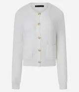 Cardigan de punto blanco, con cuello redondo, manga larga y cierre frontal de botones dorados. Posee dos bolsillos cuadrados en la parte delantera inferior.