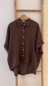 Camisa marrón de lino con botones blancos, corte holgado y mangas cortas.