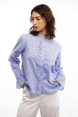 Camisa celeste de algodón con cuello mao, volados en la cartera y mangas largas con puños abotonados.