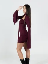 Vestido corto color borgoña, ajustado al cuerpo, con escote recto, mangas largas acampanadas y gargantilla con hebilla plateada.