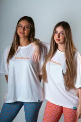 Remera blanca de manga corta con costuras a la vista color naranja y logo bordado en el pecho.