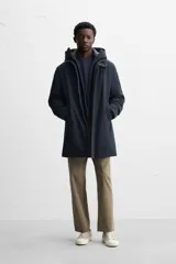 Parka azul marino de tejido técnico repelente al agua, corte regular fit, interior acolchado, cuello alto con capucha, mangas largas con puños de rib, cuello interior desmontable con cremallera, bolsillos de vivo en cadera y bolsillo interior. Cierre frontal con cremallera oculta por solapa con botones a presión.