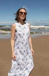 Vestido midi sin mangas con estampado floral azul sobre fondo blanco, tajos laterales y cierre con botón en la espalda.