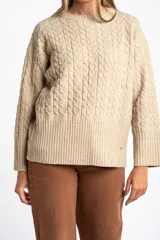 Sweater de punto color beige melange, con cuello redondo y tejido trenzado en el cuerpo y mangas. Presenta un borde inferior de punto acanalado.