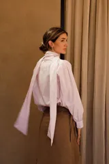 Camisa de algodón a rayas verticales rosas y blancas, con cuello alto y lazo grande en el cuello.