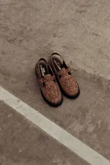 Zuecos de cuero con estampado snake, hebilla lateral metálica, puntera cuadrada y base robusta.