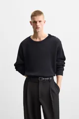 Sweater negro de punto con estructura de canalé, corte relaxed fit, cuello redondo y cierre de botones en el hombro.