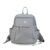 Mochila verde militar de nylon con apertura superior con cierre y tiradores metálicos. Incluye bolsillos internos, bolsillo con cierre metálico al frente, correa corta de mano y correas de galón regulables para colgar en la espalda.
