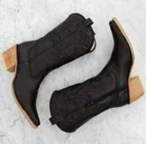 Botas texanas blancas de cuero con caña media, punta fina y cierre lateral. Presentan costuras decorativas en el empeine y el contorno de la caña.