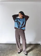 Sweater oversize tejido en punto jersey color celeste con mangas marrones y diseño de hoja abstracta en el frente.