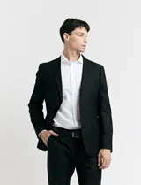 Traje de vestir color marrón topo, compuesto por saco de dos botones con solapa de muesca, dos bolsillos delanteros con solapa y un bolsillo superior. Pantalón de vestir con corte recto y bolsillos laterales. Incluye camisa blanca y corbata azul con lunares blancos.