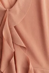 Musculosa color salmón con escote en V pronunciado, breteles anchos y detalle de volados en el escote y en el bajo de doble capa.