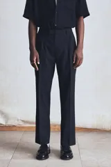 Pantalón de vestir negro de corte recto, confeccionado en mezcla de lino y algodón. Cuenta con cierre frontal con botón y gancho ocultos, bolsillos laterales y traseros ribeteados, pinzas y pliegues delanteros y traseros.