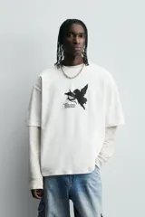 Camiseta negra de corte holgado con cuello redondo y mangas cortas. Estampado frontal y trasero con textos y figuras en color rosa.
