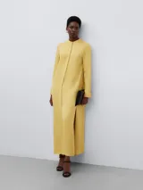 Vestido largo amarillo de viscosa con cuello mao, corte recto y abertura lateral.