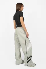 Pantalón deportivo gris de nylon, de calce recto y tiro medio, con elástico en la cintura, cordones ajustables y detalle de recorte con vivo a contratono en los laterales.