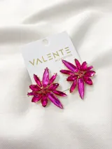 Par de aros colgantes de fantasía con forma de flor, compuestos por múltiples cristales facetados de color fucsia intenso, engarzados sobre una base metálica dorada. El centro de la flor tiene un cristal redondo más pequeño.