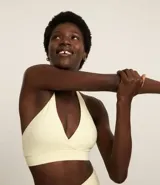 Top deportivo frente única confeccionado en microfibra color crema, con escote en V cruzado y copas removibles.