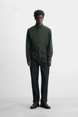 Camisa de vestir verde oscuro, corte slim fit, con cuello italiano, mangas largas con puños abotonados y cierre frontal con botones.