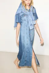 Vestido midi de denim celeste, con cuello camisero, manga corta y botonadura frontal. Presenta bolsillos superiores con solapa y botón, canesú delantero y trasero, falda acampanada y costuras decorativas.