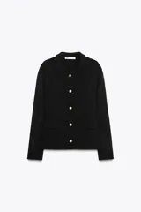 Chaqueta tipo blazer de punto color negro, con cuello solapa, manga larga, falsos bolsillos delanteros con tapetas y cierre frontal con botones dorados.