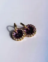 Par de aros colgantes con dije circular de resina con glitter multicolor y borde de strass. El arito es de acero quirúrgico dorado.