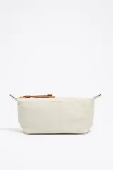 Neceser mediano de nylon color crudo, con estructura blanda, cierre de cremallera, tirador de cordón, logo metálico y acabados dorados.