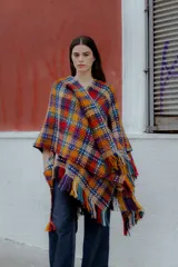 Ruana tejida multicolor con diseño geométrico y flecos.