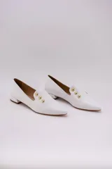 Chatitas de cuero color blanco con punta fina y apliques de tachas doradas.