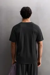 Camiseta deportiva negra de tejido técnico ligero con perforaciones, cuello redondo y manga corta.