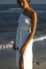 Vestido blanco de lino, largo midi, con un solo hombro, corte recto, cinturón de lazo y abertura lateral.