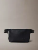 Riñonera Calvin Klein negra de cuero sintético texturizado, con cierre principal y logo CK grabado en el frente. La correa es ajustable y de color gris, con el nombre de la marca repetido.