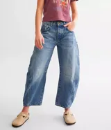 Jean de denim azul claro con lavado desgastado, tiro medio y pierna ancha. Presenta roturas y paneles con costuras visibles en la parte delantera de las piernas.