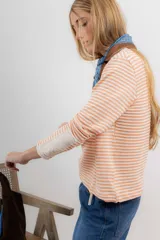 Remera de tejido de punto a rayas horizontales color naranja y blanco, de corte recto, cuello redondo y mangas largas.