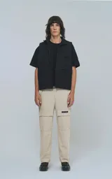 Pantalón cargo color beige con bolsillos laterales con solapa y etiqueta con texto en una de ellas.