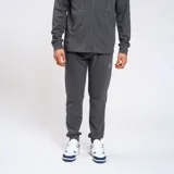 Pantalón de jogging gris con cierres laterales y trasero, y logo de la marca Umbro en la pierna izquierda.