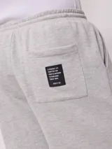 Bermuda deportiva gris confeccionada en 60% algodón y 40% poliéster, con cintura elástica ajustable con cordón.