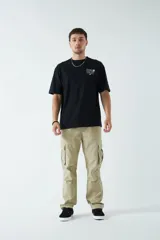 Pantalón cargo color beige, con cintura elástica ajustable con cordón, bolsillos laterales con cierre y bolsillos cargo con solapa.