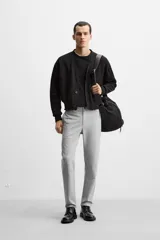 Pantalón negro de corte slim fit, confeccionado en tejido elástico. Cuenta con cintura elástica, bolsillos frontales y traseros de vivo. Cierre frontal con cremallera y botón.