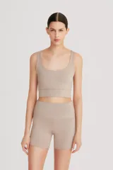 Top deportivo color beige, de cintura ancha, realizado en tela doble suave y de alta elasticidad. Detalle de breteles cruzados en la espalda.