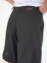 Bermuda negra de tiro medio, corte ancho, con bolsillos laterales y un ojal en la parte trasera.