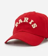 Gorra roja de sarga de algodón con visera curva, ajuste trasero y parche bordado con la palabra "Paris" en blanco.