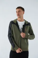Campera verde militar para hombre con capucha ajustable, cierre frontal completo, bolsillos laterales con cierre y logo estampado en el pecho. Presenta detalles en negro en la parte superior del pecho, hombros y mangas.